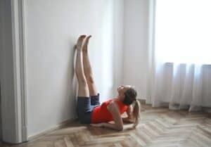 woman in workout clothes leaning up on elbows with her legs straight up against the wall